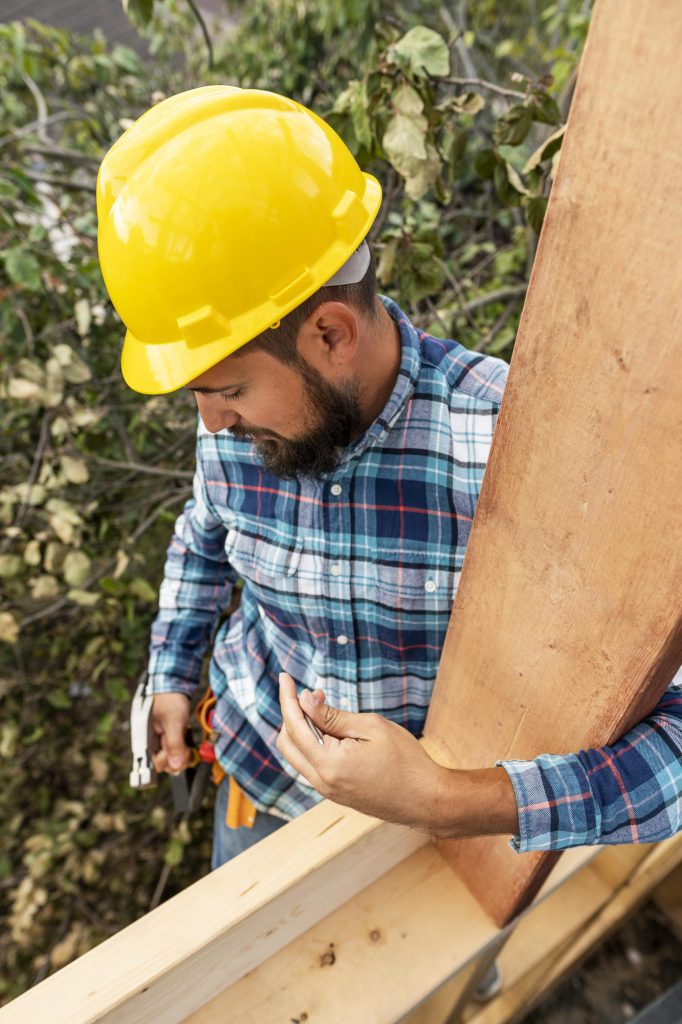 Charpentier contrôlant une pièce de bois de charpente